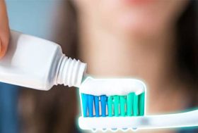 Mujer echando pasta de dientes sobre un cepillo