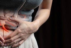 Apendicitis: mujer con las manos en el abdomen y el apéndice sobre ella