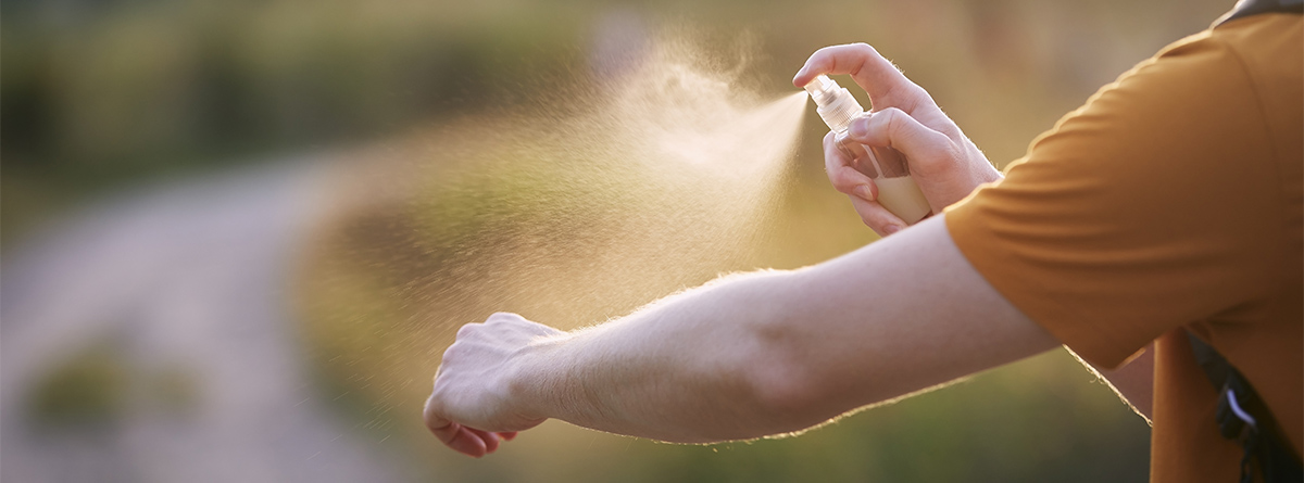 Mano pulverizando un espray sobre el otro brazo