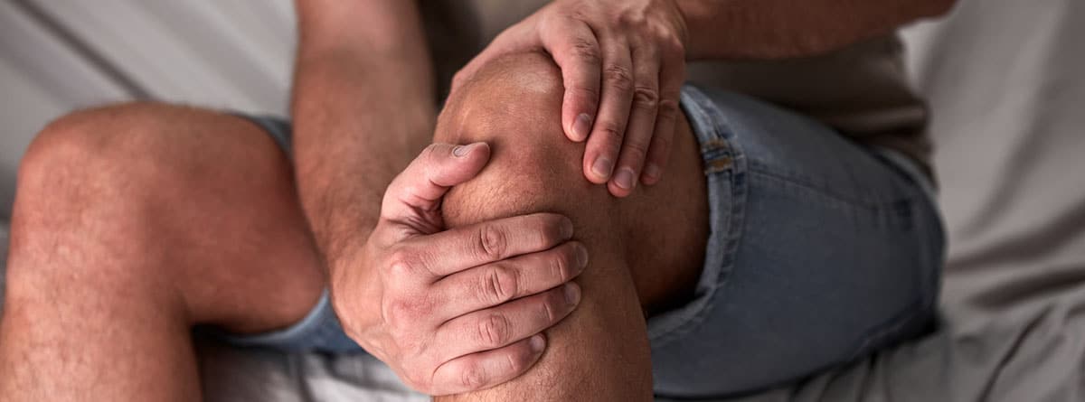 Artritis idiopática: joven con dolor en la rodilla sujetándola con las manos