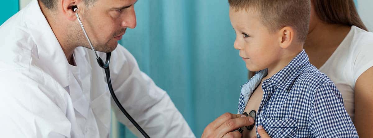 Médico revisando los latidos de corazón de un niño con un estetoscopio