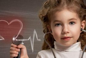 niña dibujando en la pizarra un corazón con latido