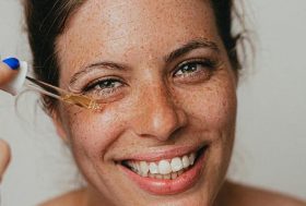 Mujer joven poniéndose un producto cosmético en la cara