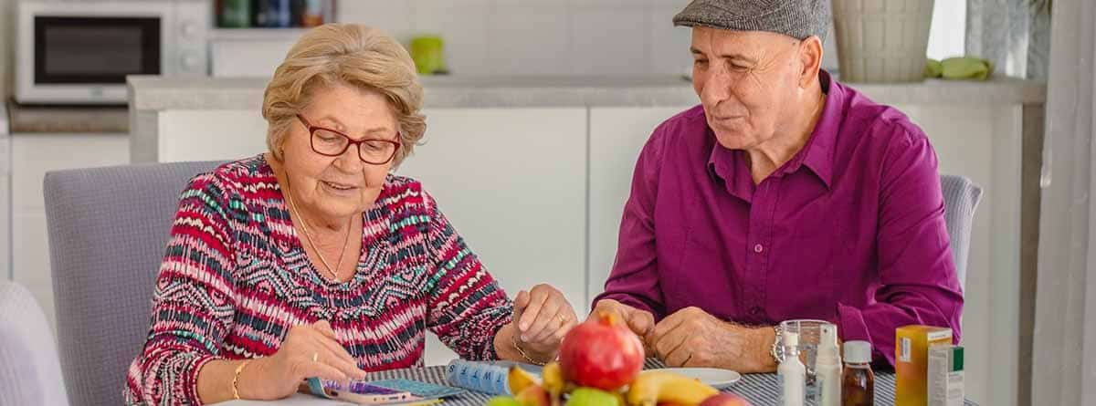 Pareja mayor sentados en una mesa con fruta