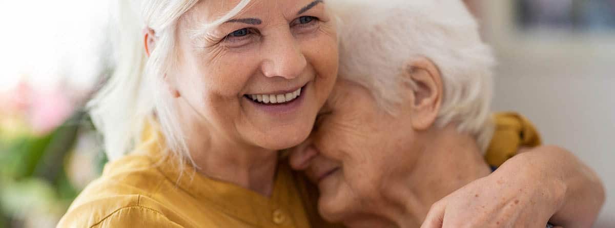 Personas mayores abrazadas y sonrientes