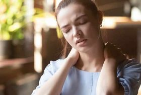 Mujer con cara de dolor tocándose el cuello