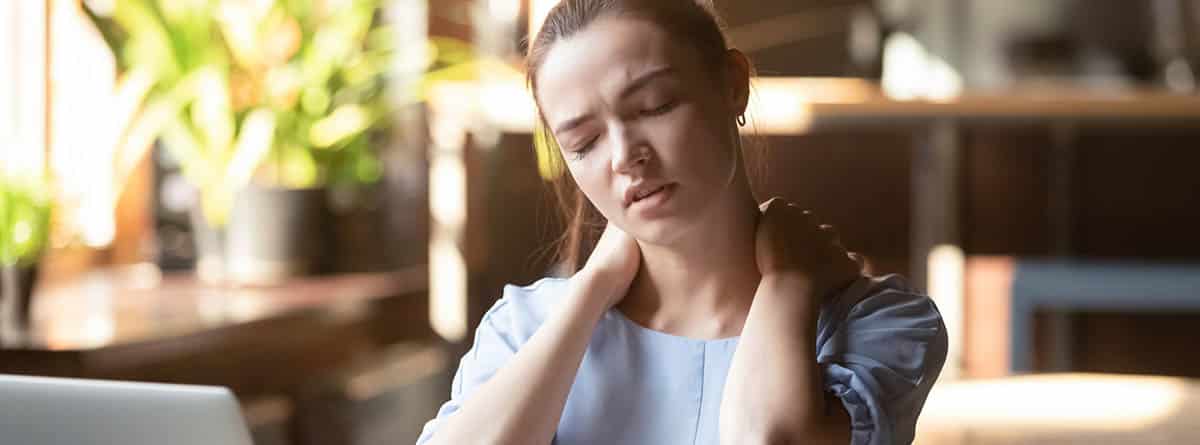 Mujer con cara de dolor tocándose el cuello