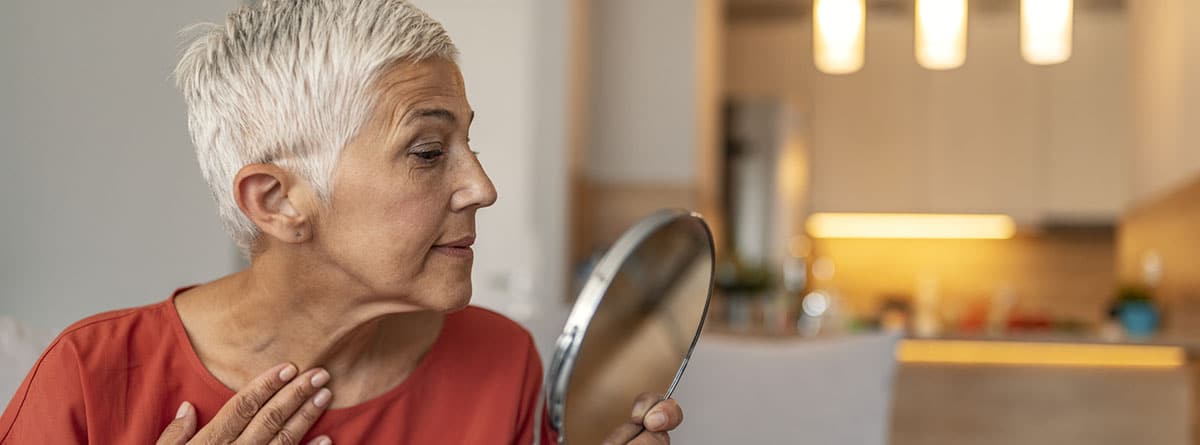 Mujer madura, con cabello blanco mirándose en un espejo