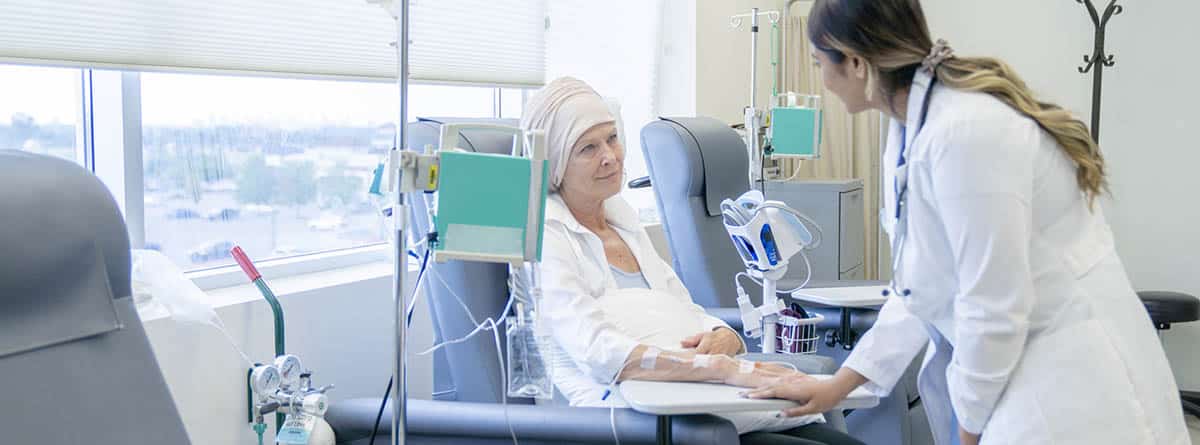 Mujer con un pañuelo en la cabeza recibiendo un tratamiento de quimioterapia