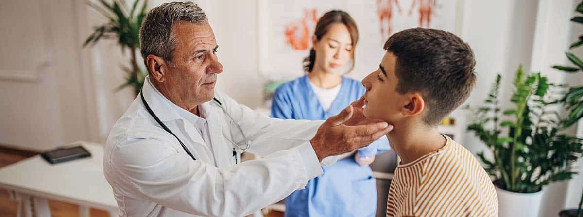 Médico examinando la garganta de un adolescente