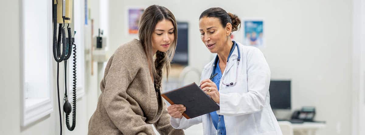 Una doctora habla con una paciente y le muestra unas anotaciones