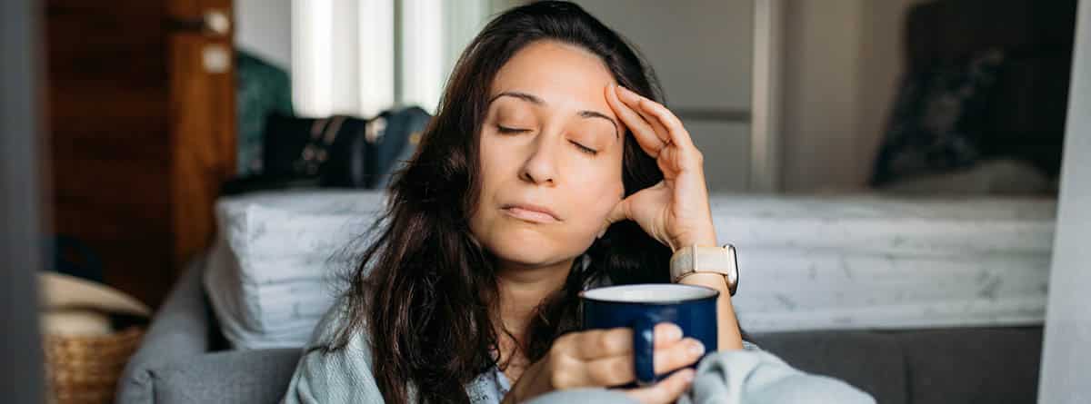 Mujer con cara de enferma con una taza en las manos