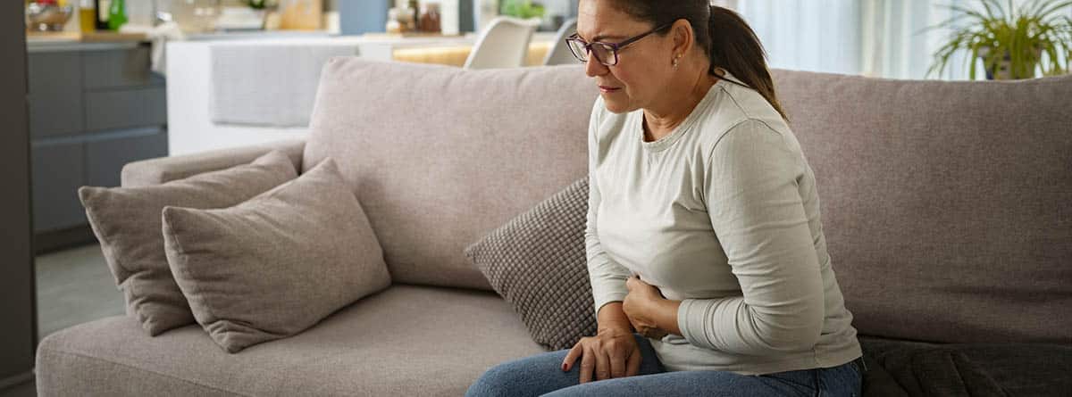 Mujer tocándose la tripa con gesto de dolor