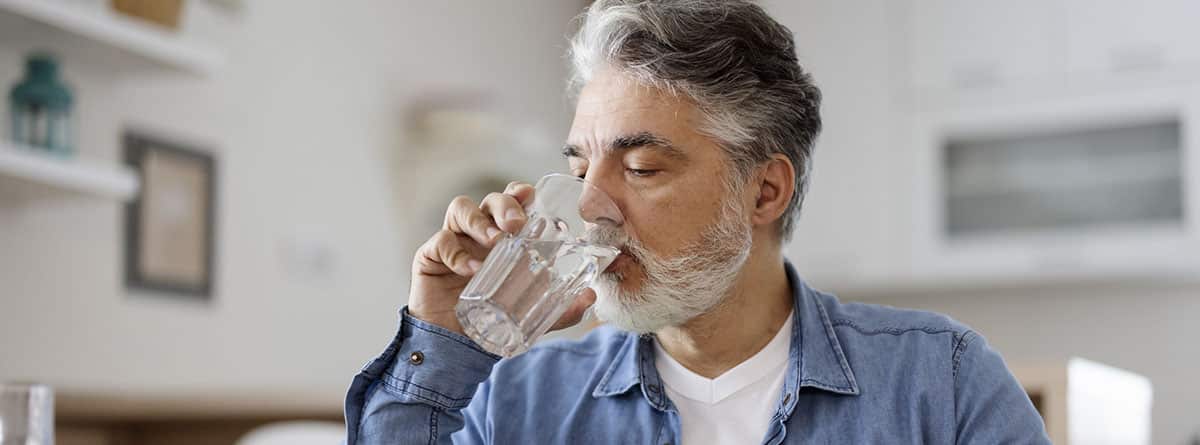 Señor canoso bebiendo un vaso de agua