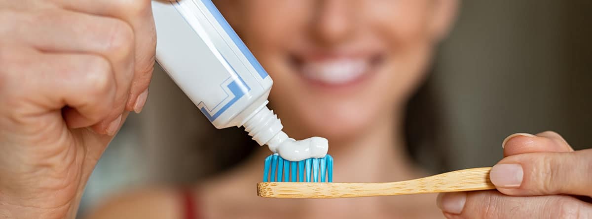 Mujer poniendo pasta de dientes sobre un cepillo